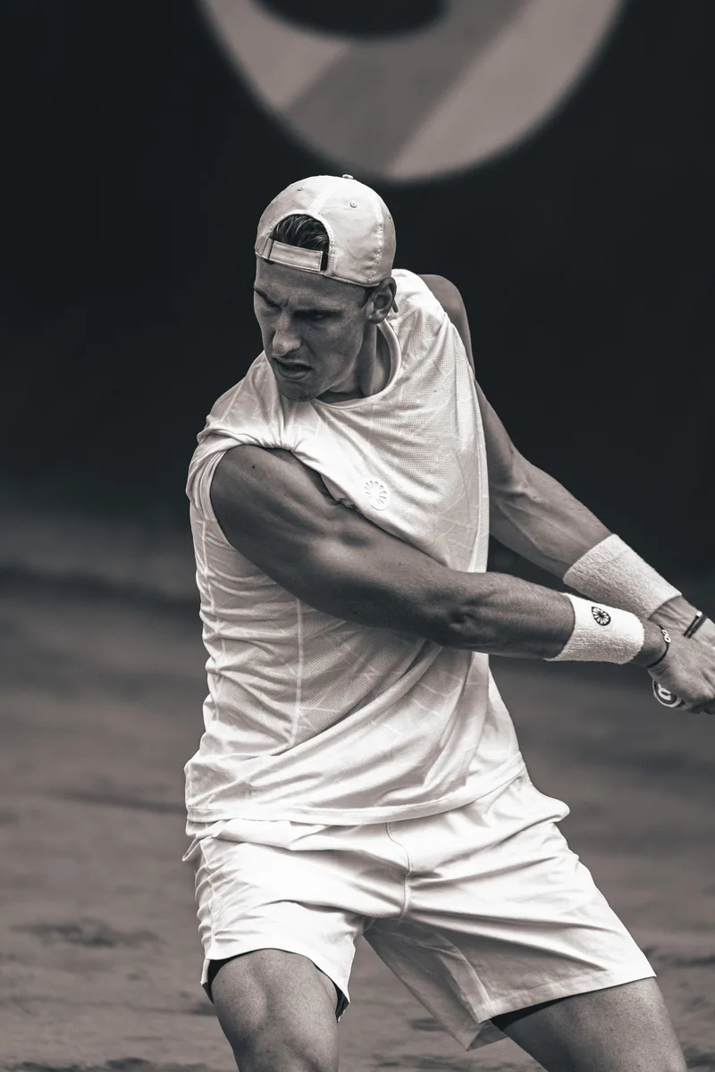Zwart-wit opname van een tweehandige backhand op gravel