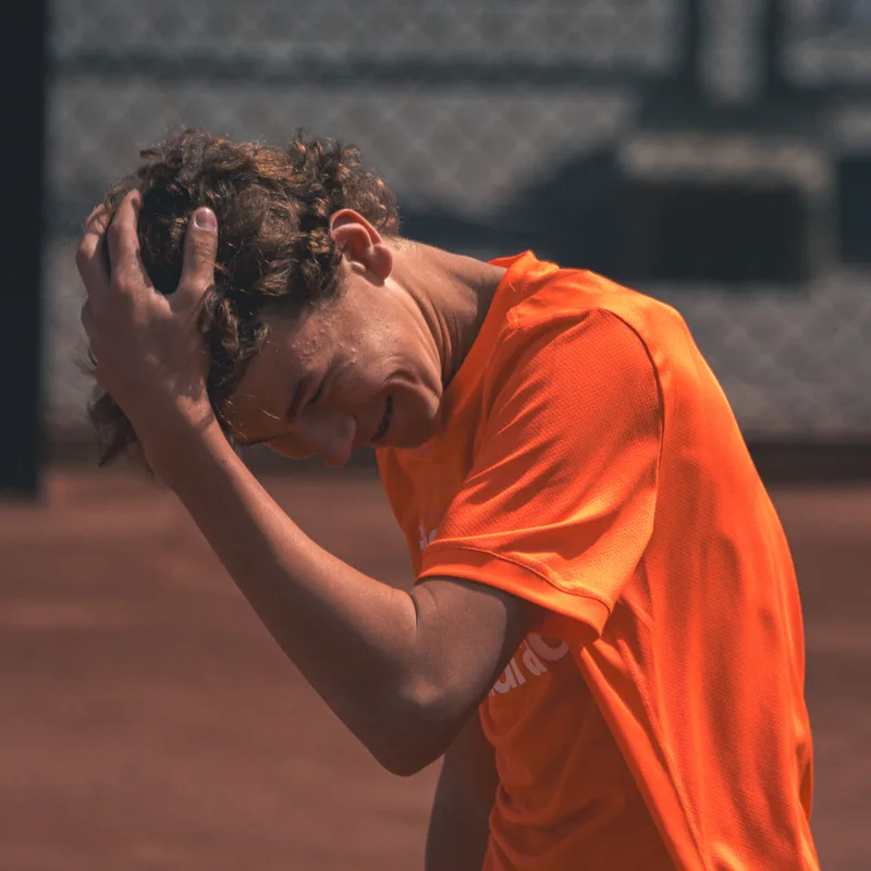 Speler in oranje shirt met de hand in het haar na een verloren punt