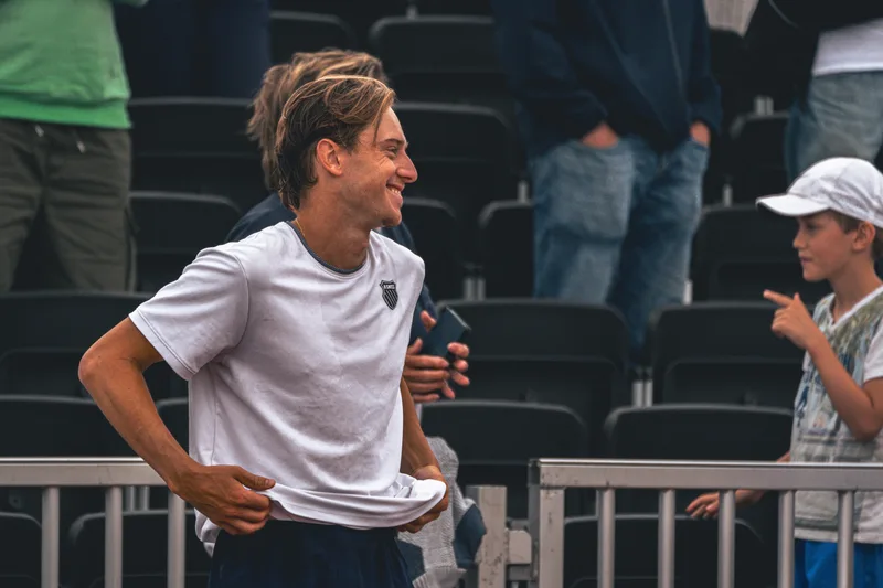 Speler lacht na afloop van de wedstrijd terwijl een jonge fan toekijkt