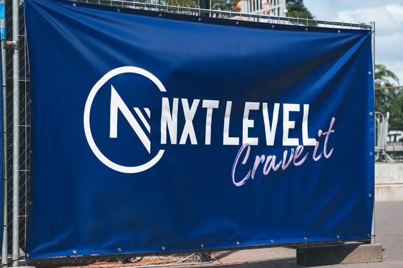 Sponsordoek van NXT LEVEL langs de baan op het toernooiterrein