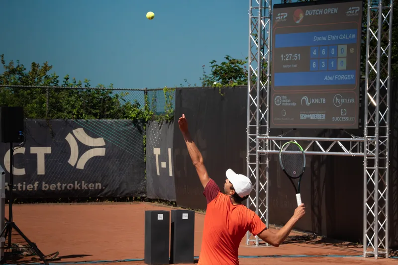 Speler in oranje shirt slaat op voor het scorebord van het Dutch Open Tournament