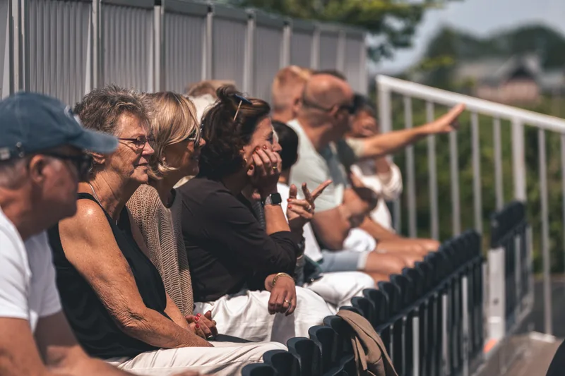 Toeschouwers volgen de wedstrijd staand langs het hek