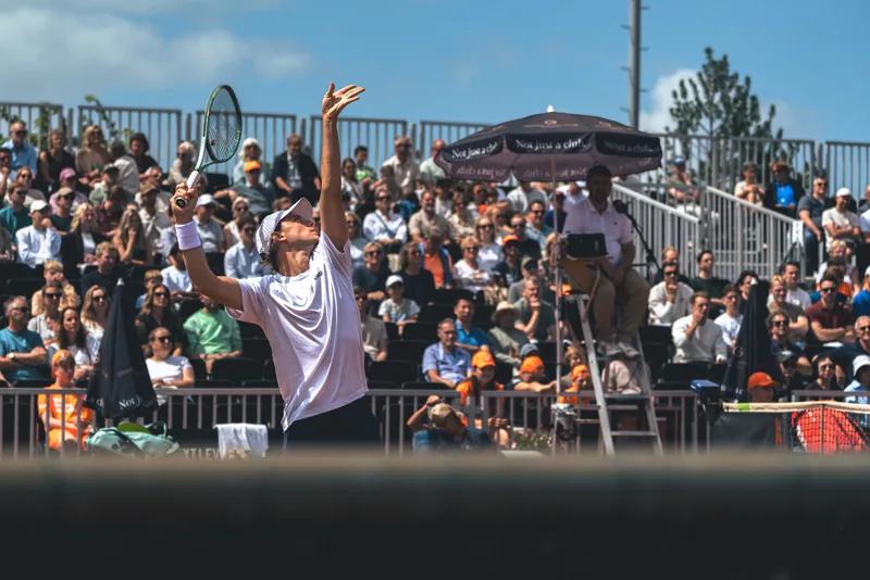 Speler serveert voor een volle tribune tijdens de finaledag van het Dutch Open Tournament